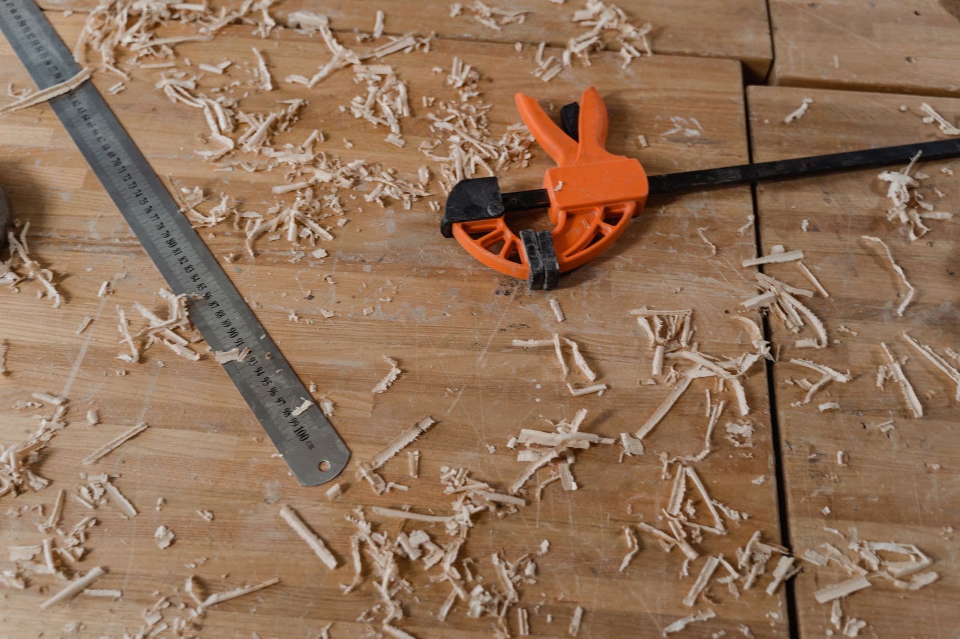 Close-up of woodworking tools on a wooden workbench with scattered sawdust.