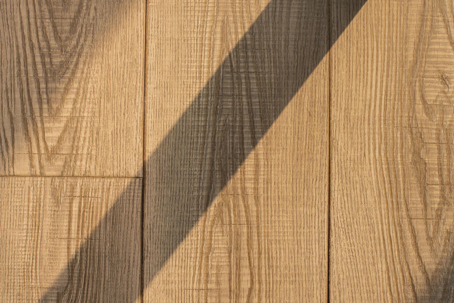 Detailed view of wooden floor planks with a dramatic shadow, showing natural texture.