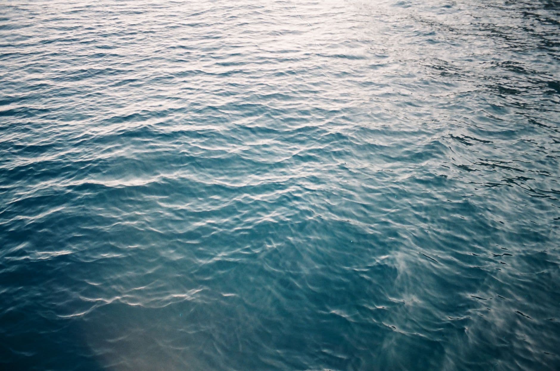 Serene image of blue ocean waves reflecting sunlight, creating a soothing texture.