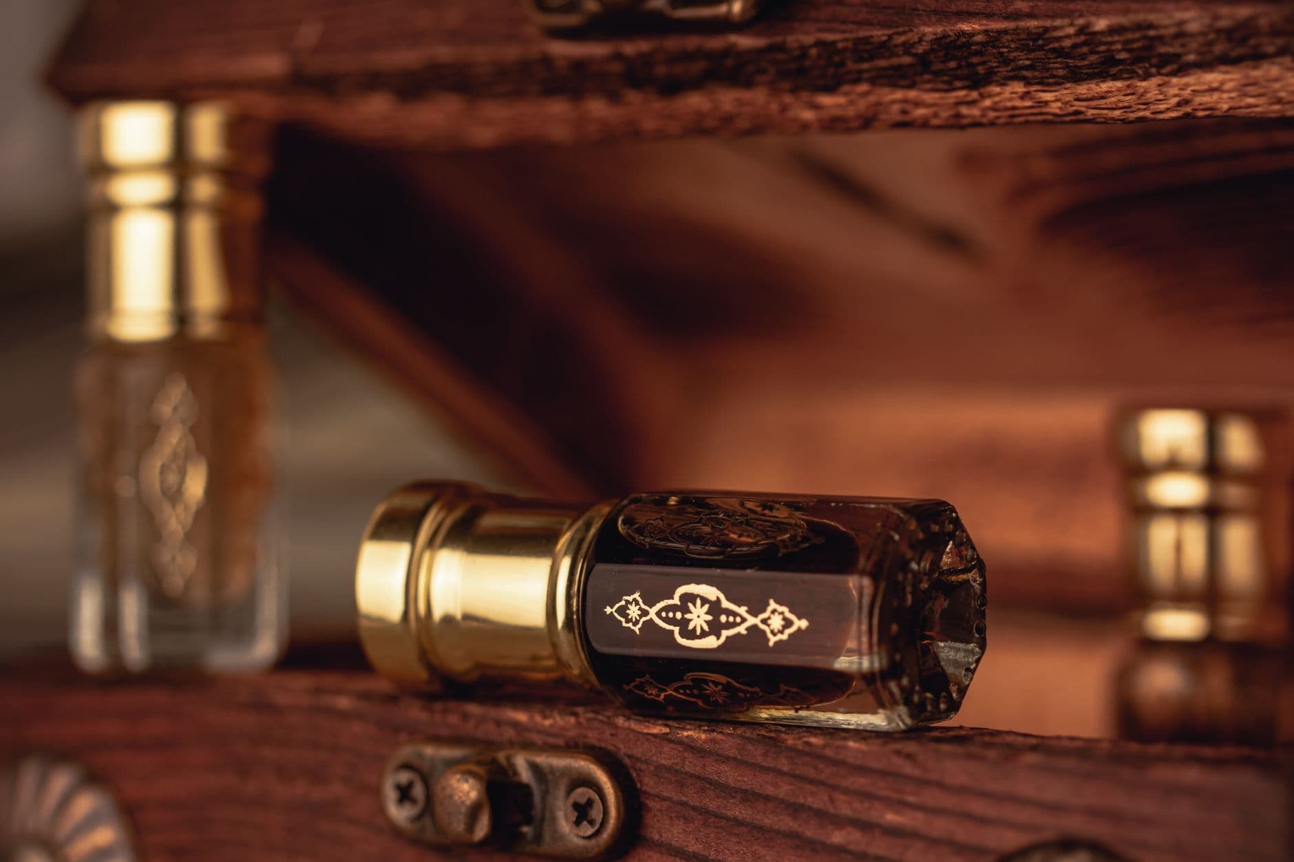 Close-up of vintage perfume bottles displaying intricate golden designs, set on a wooden surface.