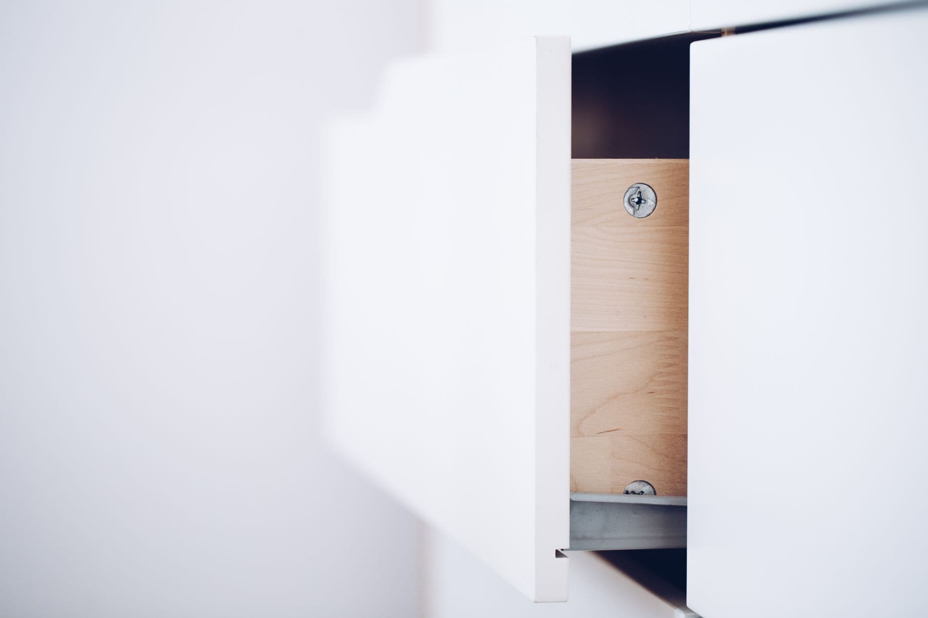 A plain white drawer pulled part way open against a pale wall