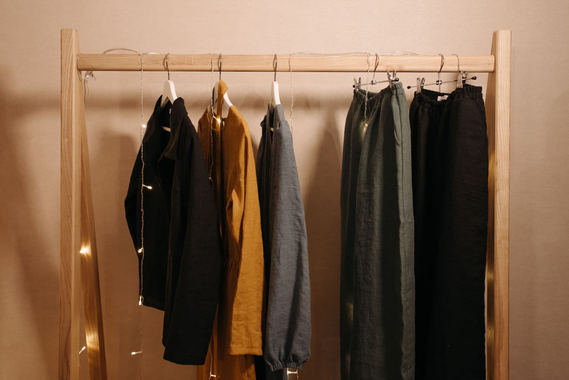 A rack of plain linen clothes on wooden hangers in warm light