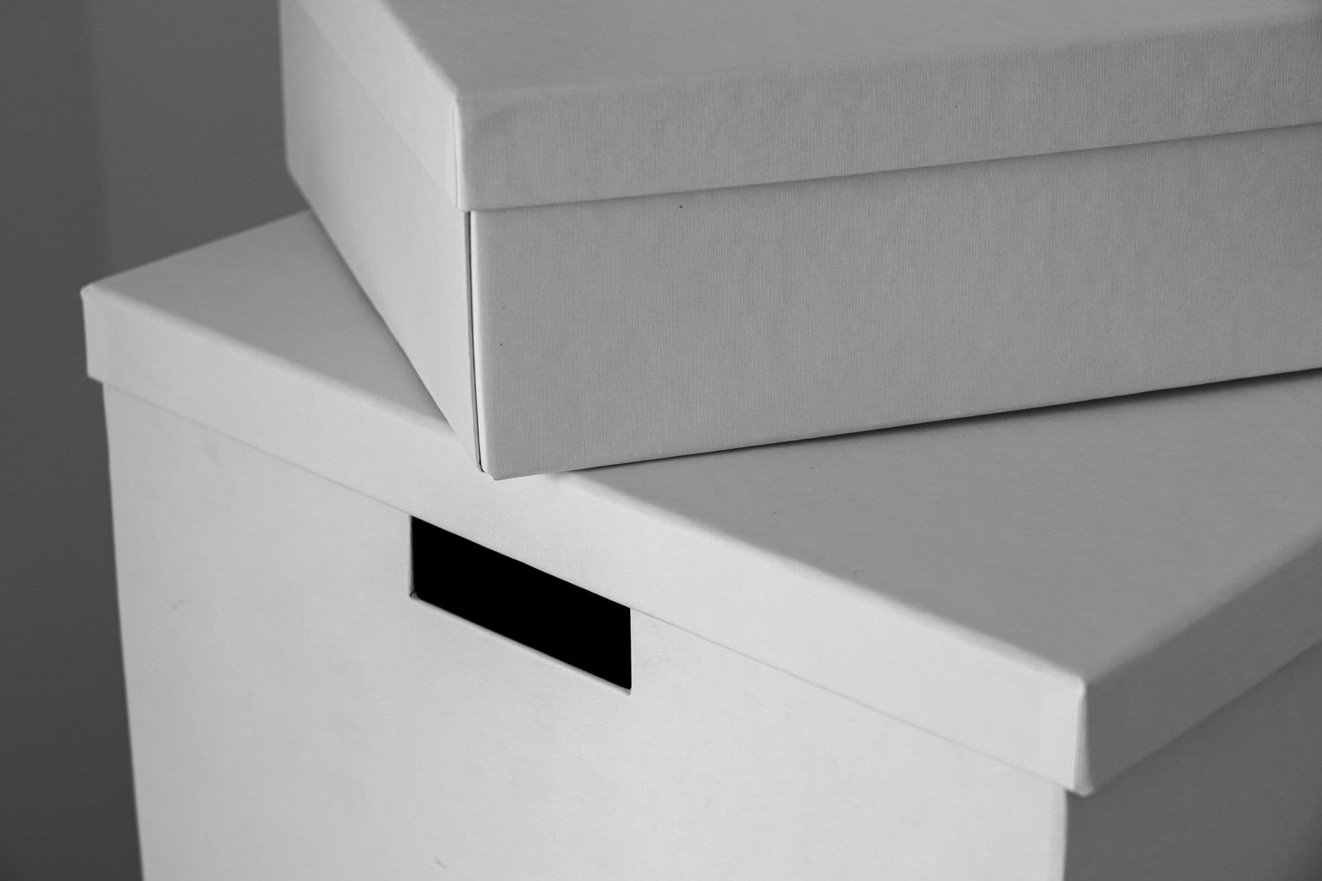 Two plain white cardboard boxes stacked against a pale wall