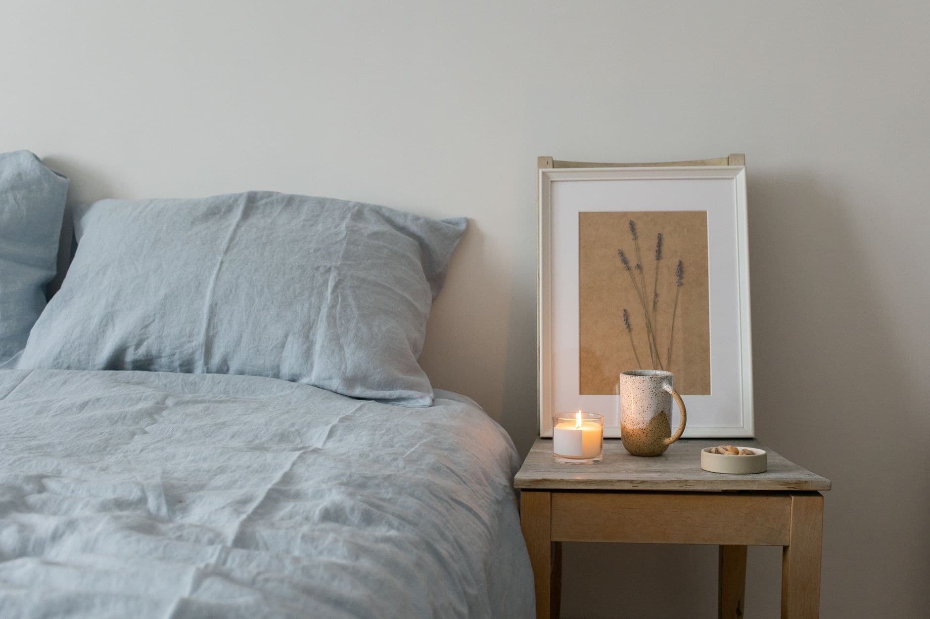 A candle and folded linen on a timber table in soft light